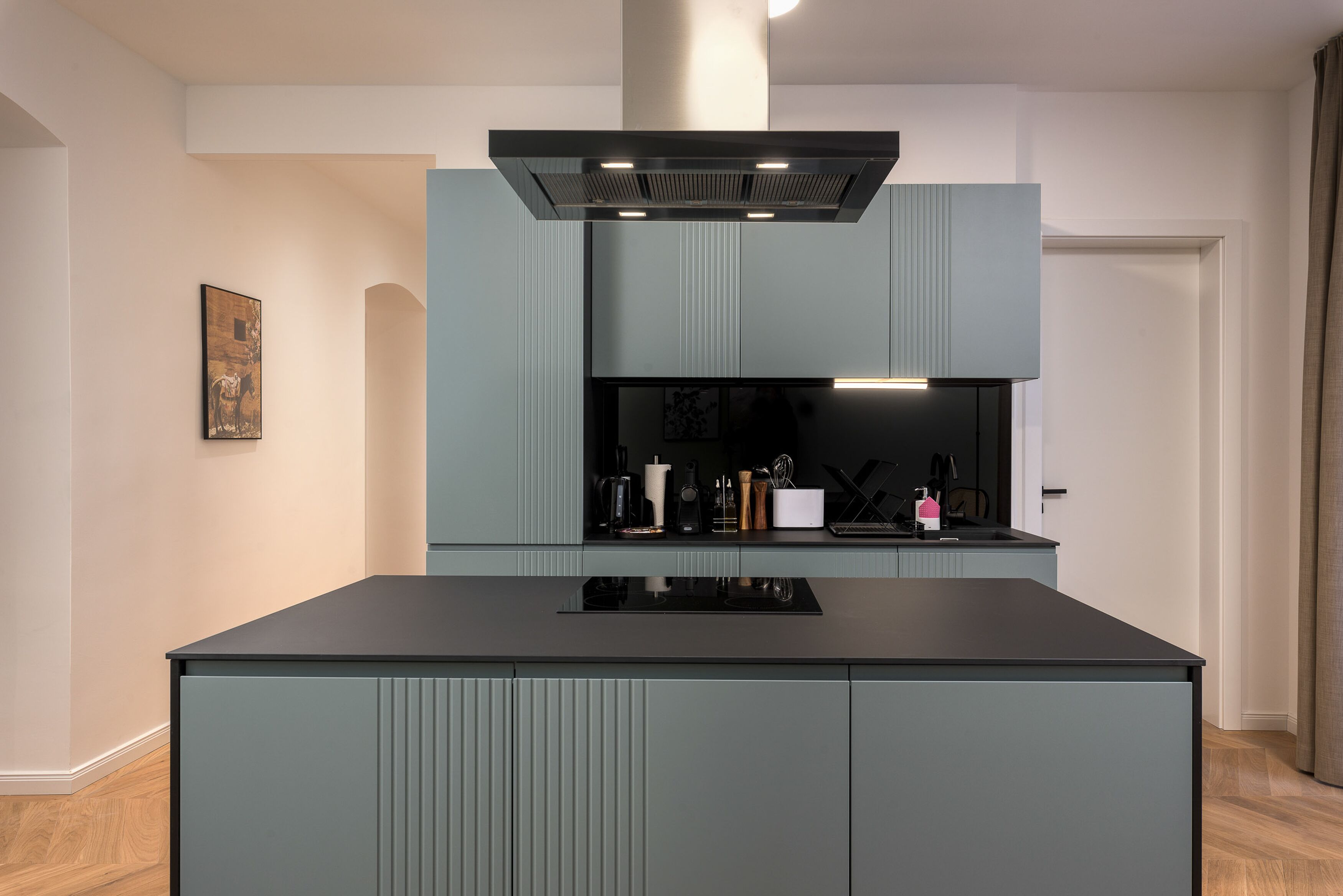Une cuisine moderne dotée d’un îlot central, de meubles de rangement intégrés et d’une hotte en acier inoxydable.