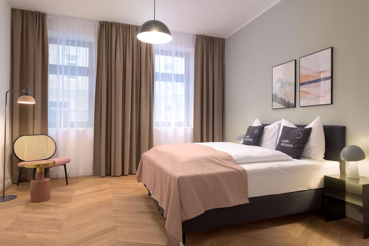 Une chambre moderne avec un lit, une chaise, un bureau et une grande fenêtre avec des rideaux.