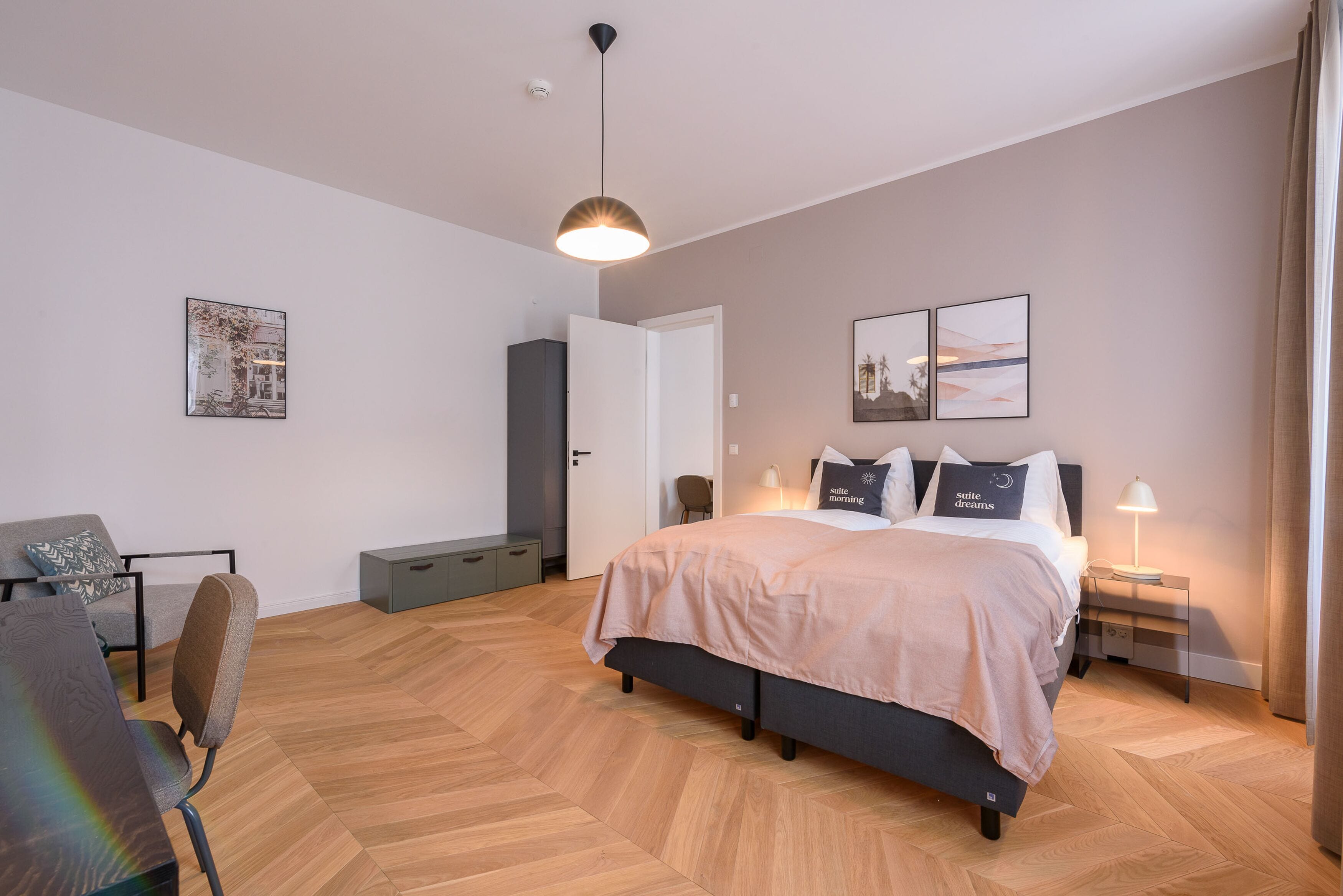 A modern bedroom with a bed, bedside tables, a desk, and a chair.