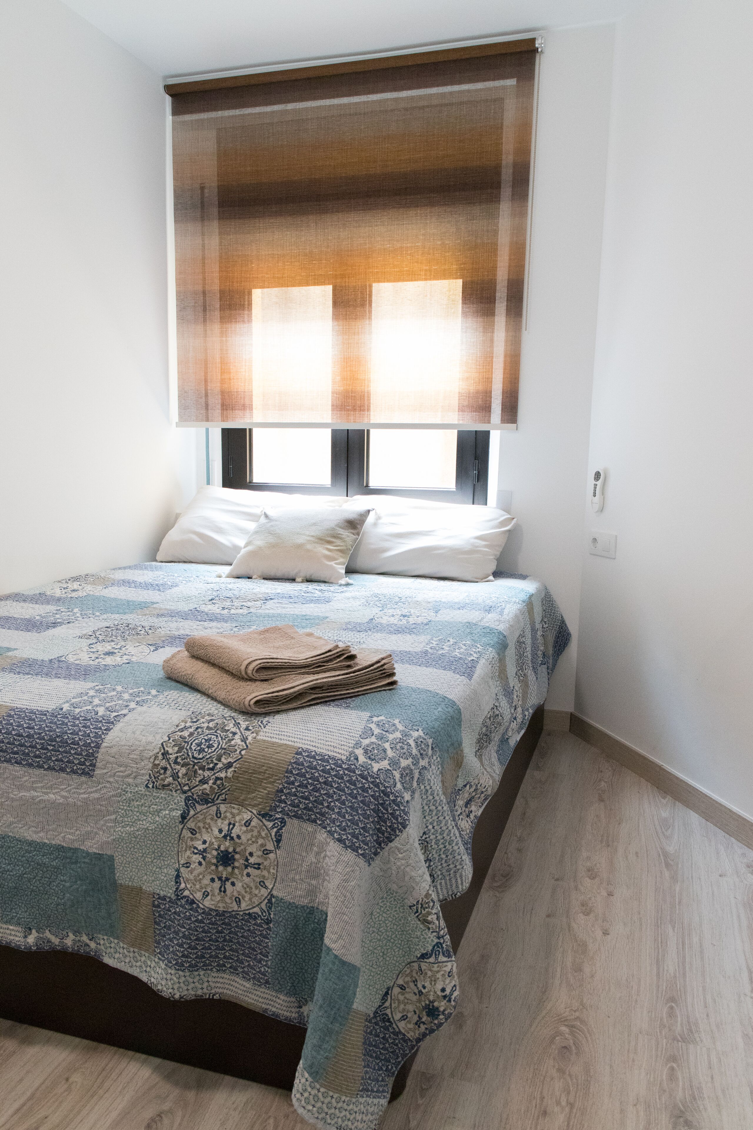 Ein Schlafzimmer mit Bett, Fenster mit Jalousien und Nachttisch.