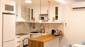 A modern kitchen with white cabinetry, a wooden island, and pendant lighting. - Figueres Center A 4-minute walk from the Dalí Museum! Spirals Stairs Duplex terrace (Figueres)