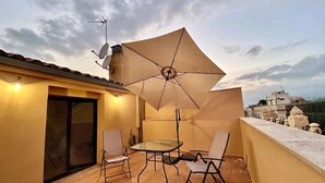 A balcony with a glass table and chairs, an umbrella, and a satellite dish. - Figueres Center A 4-minute walk from the Dalí Museum! Spirals Stairs Duplex terrace (Figueres)