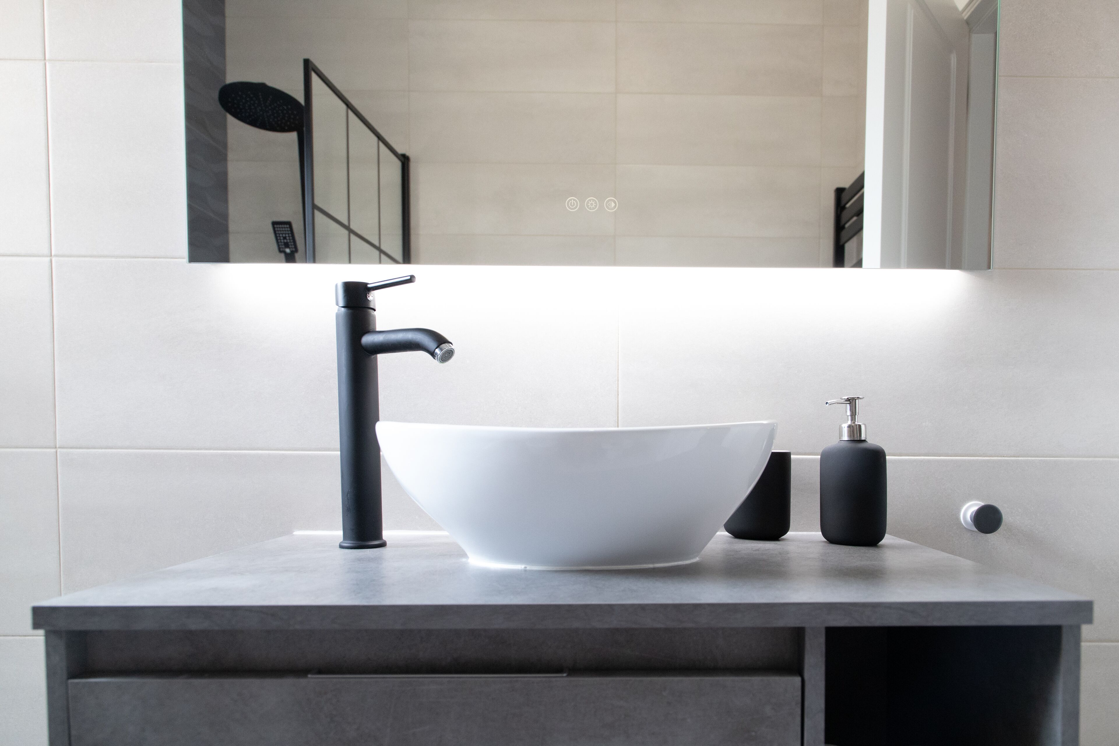 A modern bathroom with a white sink, black faucet, and a mirror above.