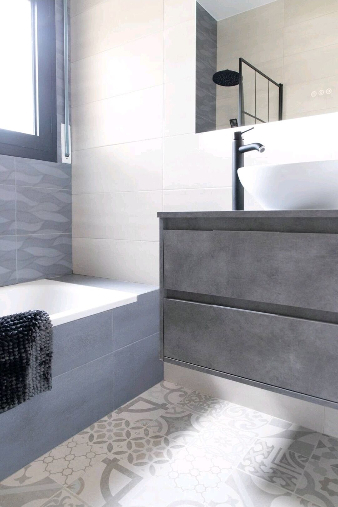 A modern bathroom with a bathtub, a large mirror, and a vanity with a sink.
