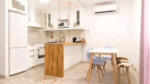 A compact kitchen with white cabinets, a wooden island, and a dining area with a table and chairs. - Figueres Center A 4-minute walk from the Dalí Museum! Spirals Stairs Duplex terrace (Figueres)