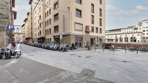 A building with multiple floors, a row of parked motorcycles, and a sign for a wine store. - Studio Suite With Elevator Near the Old Bridge (Florence)