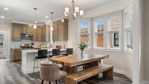 A modern kitchen with wooden cabinets, a central island, and pendant lighting. - Seabrook Salt and Vine | Pet Friendly, Fire Pit, Single Level, EV Charger, 3BR (Pacific Beach)