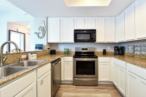 A kitchen with white cabinets, stainless steel appliances, and a granite countertop. - 3rd Floor w/ 2 King Beds Near The Elevator at Palms of Destin! (Destin)