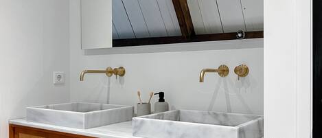 Un baño con dos lavamanos, un espejo grande y un mueble de tocador de madera.