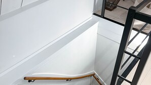 Una escalera moderna con barandilla de madera y balaustradas de metal, que conduce a un nivel superior con piso de madera.