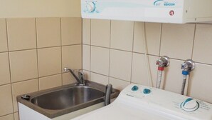 Un espace buanderie comprenant un lave-linge, un évier et un radiateur fixé au mur.