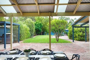 An outdoor patio with a covered dining area, a barbecue grill, and a well-maintained lawn. - Willunga Cottage- Sleeps 6, Pool (Willunga)