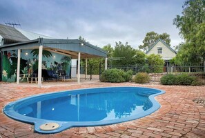 A swimming pool with a covered patio area, a brick pathway, and a house in the background. - Willunga Cottage- Sleeps 6, Pool (Willunga)