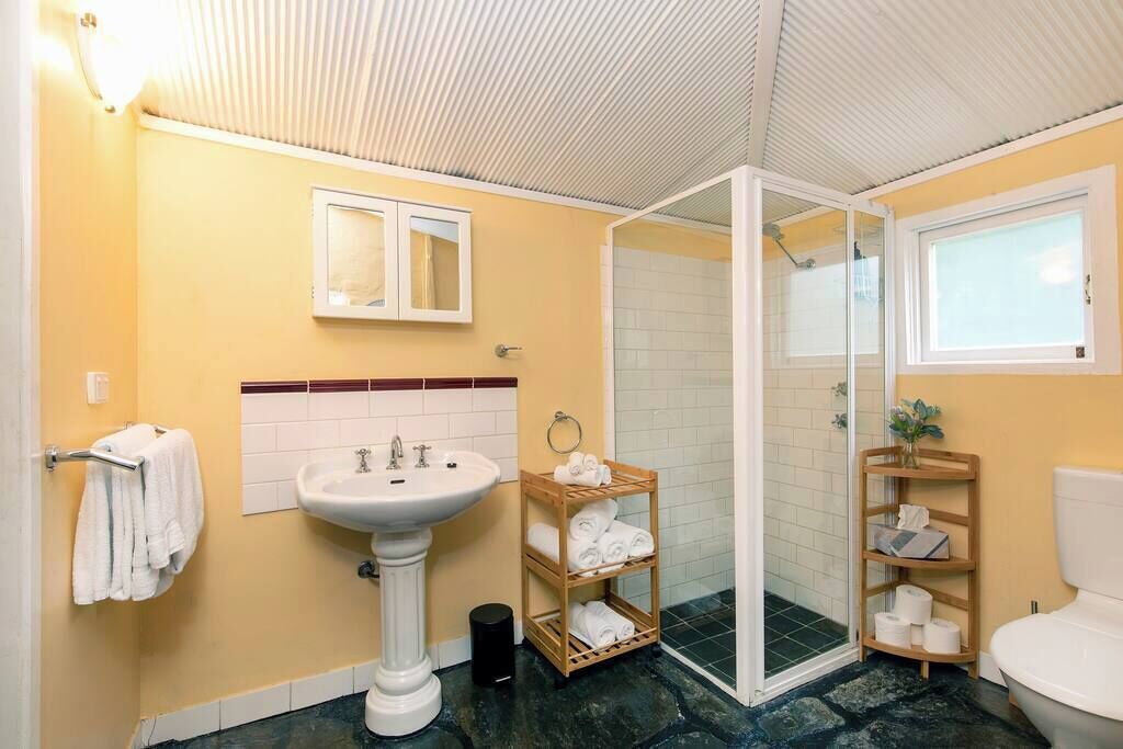 Une salle de bain comprenant un lavabo sur colonne, une cabine de douche en verre, des toilettes et un porte-serviettes.