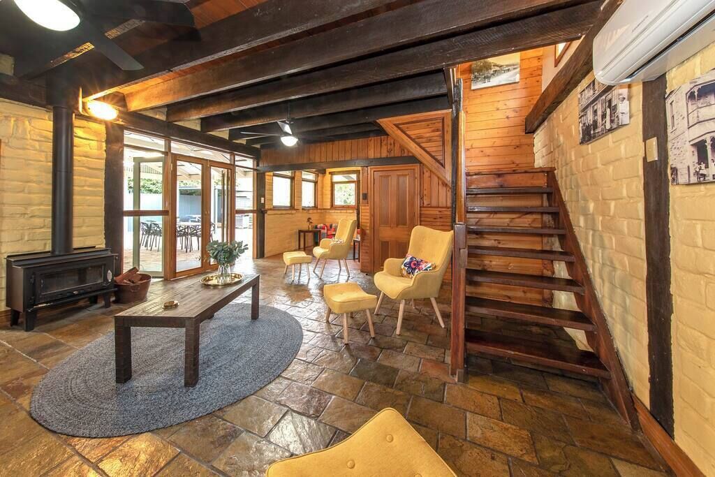 A cozy interior with a fireplace, wooden furniture, a staircase, and a stone floor.