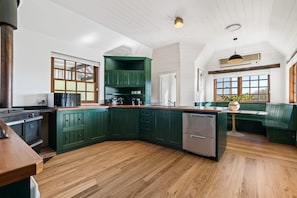Eine Küche mit grünen Schränken, einer Holzausziehtheke, einem eingebauten Geschirrspüler und einem Fenster mit Blick.