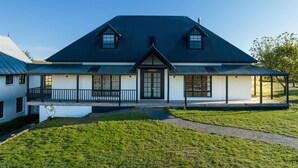 A two-story house with a dark roof, a front porch, and a small garden area. - Old Alloway House - Sleeps 11 - Farm Stay (Eglinton)