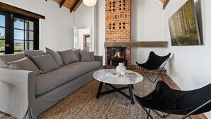 A cozy living room with a brick fireplace, a sofa, a round coffee table, and a black chair. - 'Old Alloway'- 7 Bedrooms/ Sleeps 17 -9mins to CBD (Eglinton)