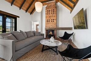 A cozy living room with a brick fireplace, a sofa, a round coffee table, and a black chair.