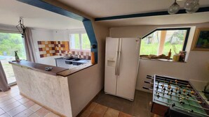 A compact kitchen with a central island, a refrigerator, and a foosball table. - Villa with swimming pool and private river (Prémian)