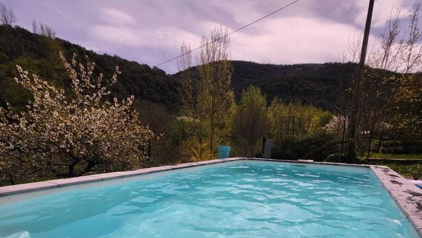 A swimming pool with clear water, surrounded by trees and hills. - Villa with swimming pool and private river (Prémian)