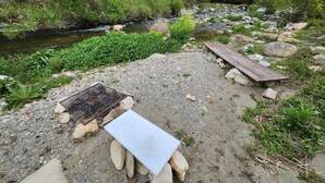 A natural outdoor area with a gravel path, a wooden bench, and a grill. - Villa with swimming pool and private river (Prémian)