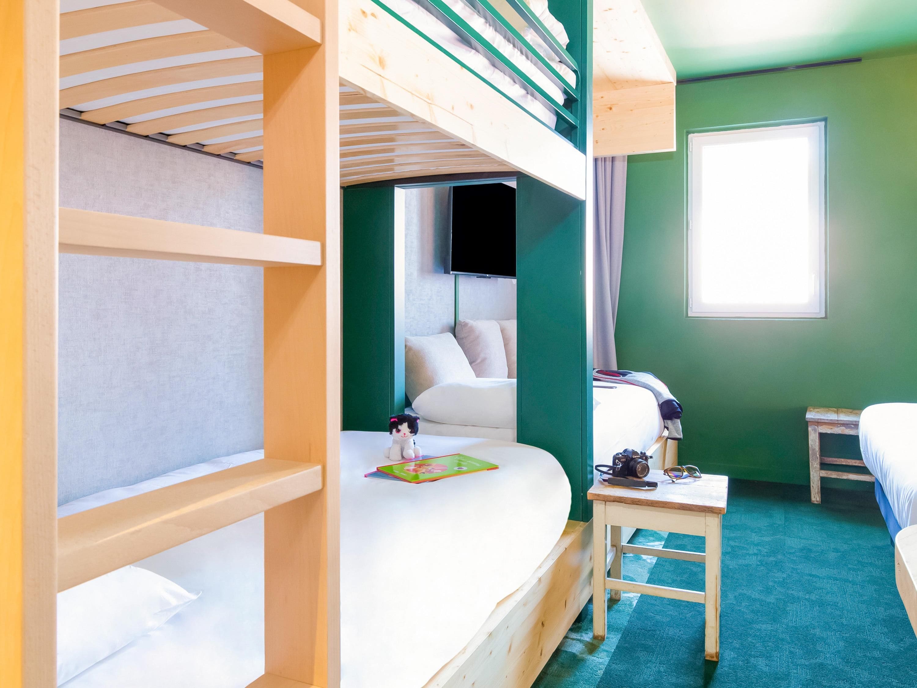 Habitación con literas, una mesita pequeña y una ventana.