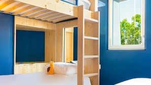 Habitación con literas, una ventana, una escalera de madera y un pequeño juguete naranja sobre la cama.