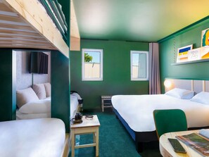 Quarto de hotel com duas camas, uma mesinha, uma cadeira, uma televisão e uma janela.