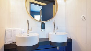 A bathroom with two sinks, a mirror, and a towel rack. - ibis Styles Salon de Provence (Salon-de-Provence)