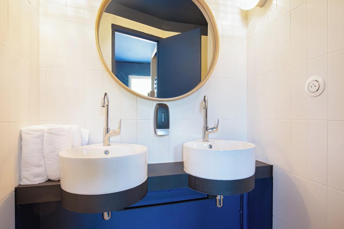 Un baño con dos lavamanos, un espejo y un perchero para toallas.