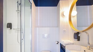 A bathroom with a glass-enclosed shower, a white toilet, and a sink with a mirror. - ibis Styles Salon de Provence (Salon-de-Provence)