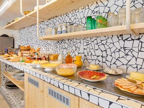 Un buffet proposant une variété de plats et de boissons, un mur recouvert de carreaux et des étagères en bois.