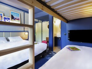 A hotel room with bunk beds, a flat-screen TV, a bathroom with a sink and mirror, and a bookshelf with travel-themed books. - ibis Styles Salon de Provence (Salon-de-Provence)