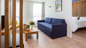 Una sala de estar moderna con un sofá, una mesa de centro y una cama con cabecera de madera.