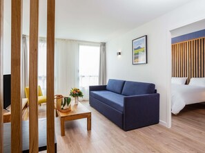 Ein modernes Wohnzimmer mit einer Couch, einem Couchtisch und einem Bett mit Holz Kopfteil.