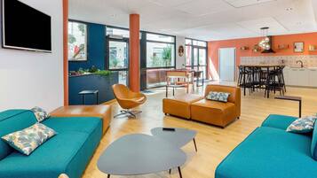 A modern lounge area with teal sofas, a brown leather couch, and a black coffee table.