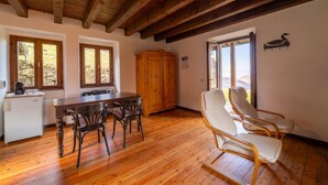 Ein Holzespeisesaal mit Stühlen, ein Holzschrank und ein Blick ins Freie durch Fenster.