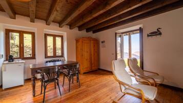 Una mesa de comedor de madera con sillas, un aparador de madera y vistas al exterior a través de ventanas.