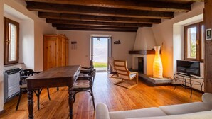 Ein gemütliches Wohnzimmer mit Holztisch, Stühlen, einer Couch, einem Kamin und einem Fernseher.
