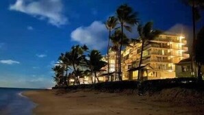 A beachfront hotel with multiple floors and balconies, surrounded by palm trees. - Beachfront Condo with Amazing View (Hauula)