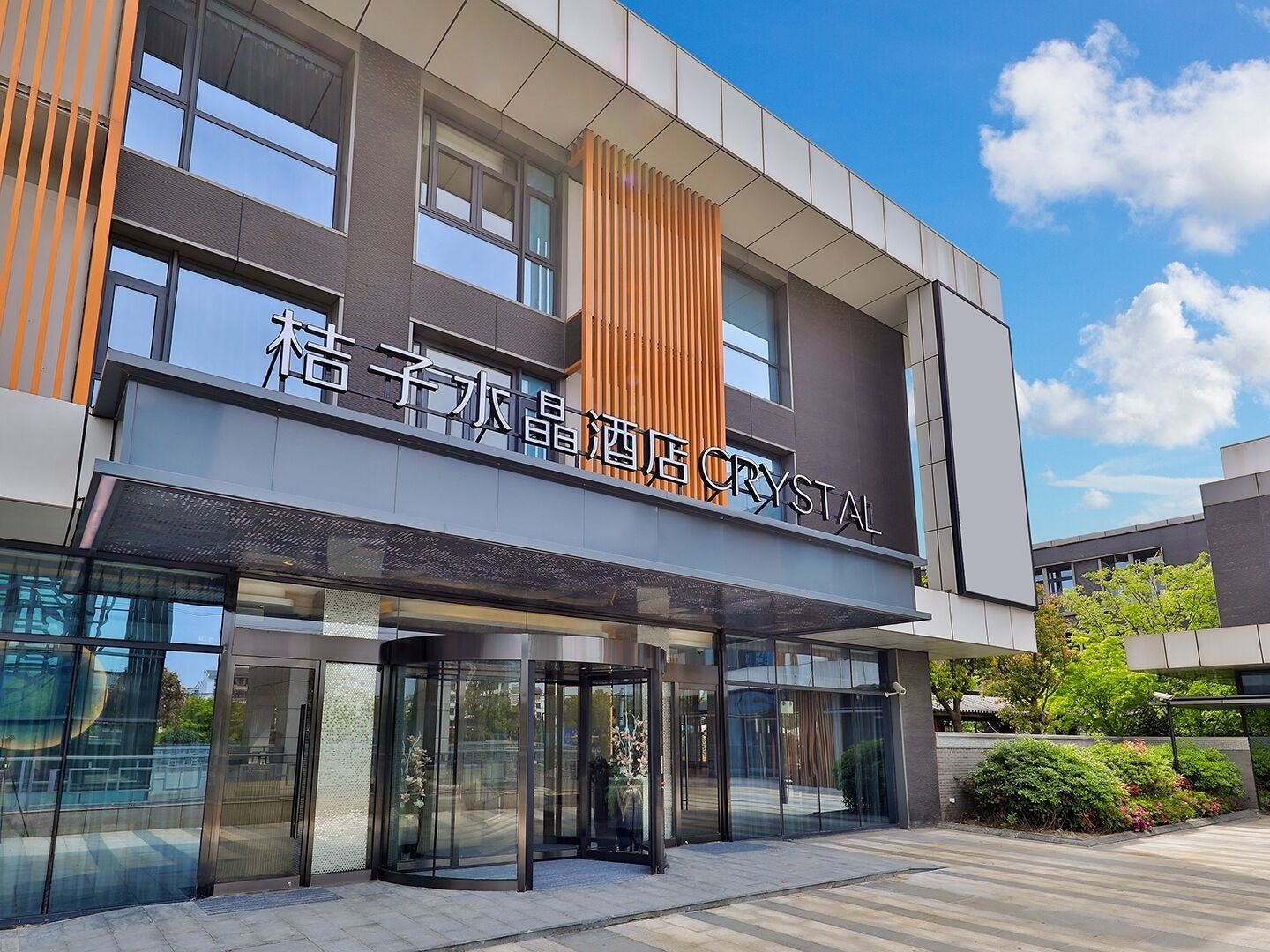 A modern building with a glass entrance and a sign that reads 'Crystal Hotel'.