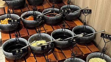 A variety of condiments and sauces arranged in stone bowls on a wooden rack.
