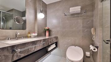 Un baño moderno con lavamanos doble, inodoro, cabina de ducha con mampara de vidrio y perchero para toallas.