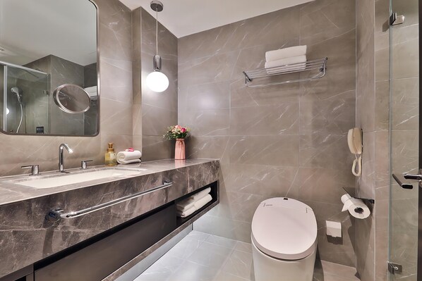 A modern bathroom with a dual sink vanity, a toilet, a glass shower enclosure, and a towel rack.