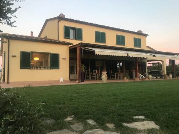 Un bâtiment à deux étages doté d’un patio couvert, d’une pelouse et d’un espace aménagé pour s’asseoir à l’extérieur.