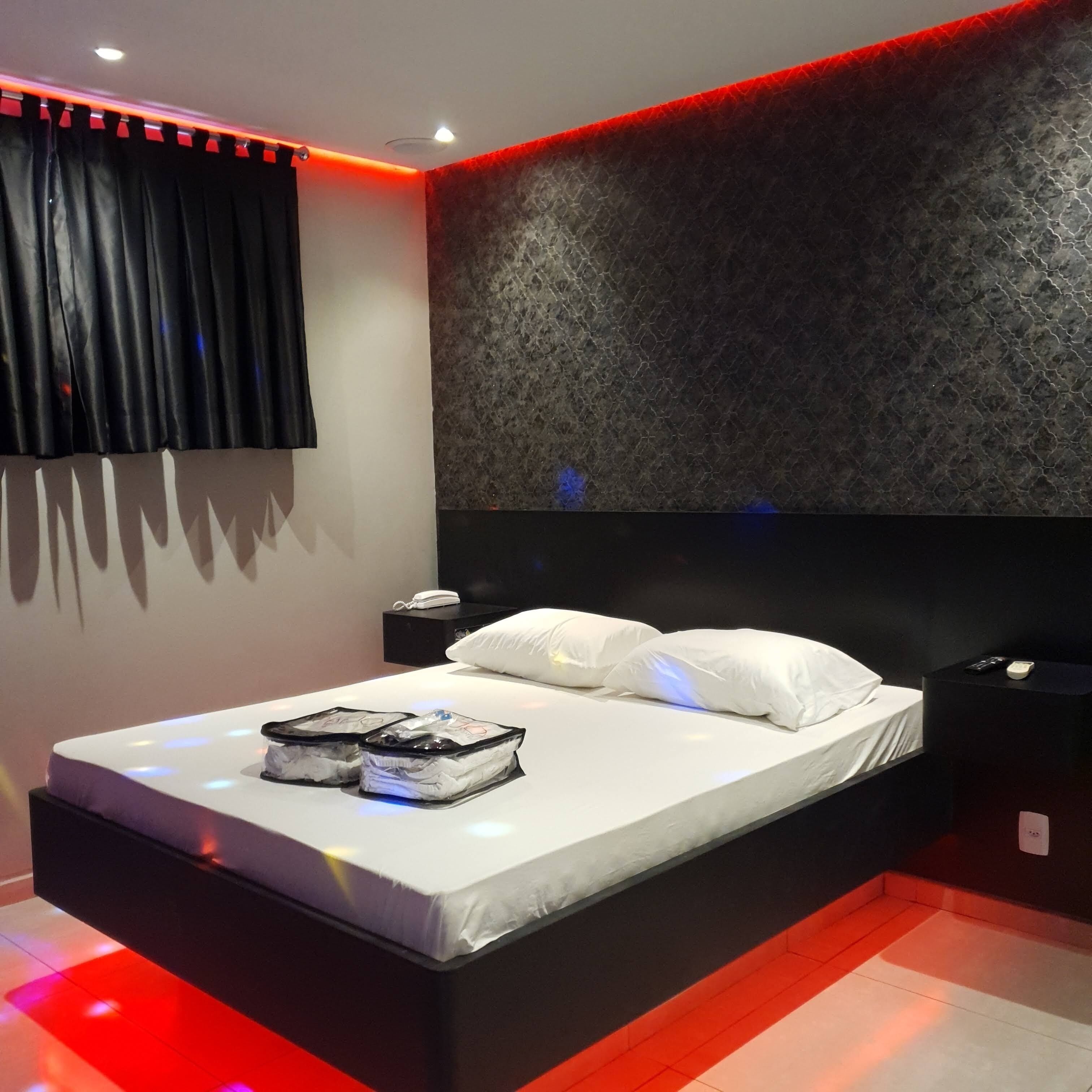 A modern bedroom with a large bed, black nightstands, and a textured wall.