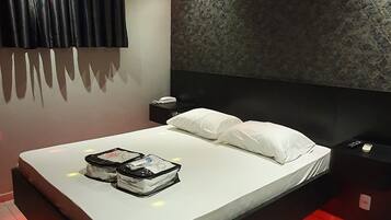 Une chambre moderne avec un grand lit, une tête de lit au motif texturé et un éclairage d’ambiance rouge.