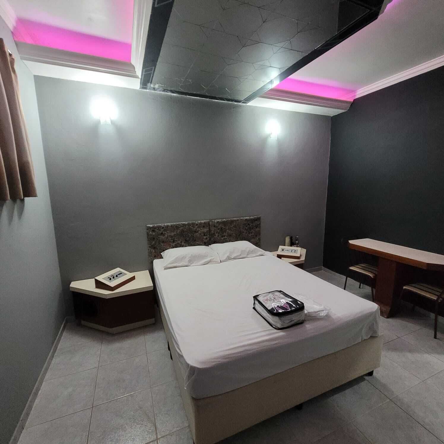 A modern hotel room with a bed, bedside tables, a desk, and a chair.