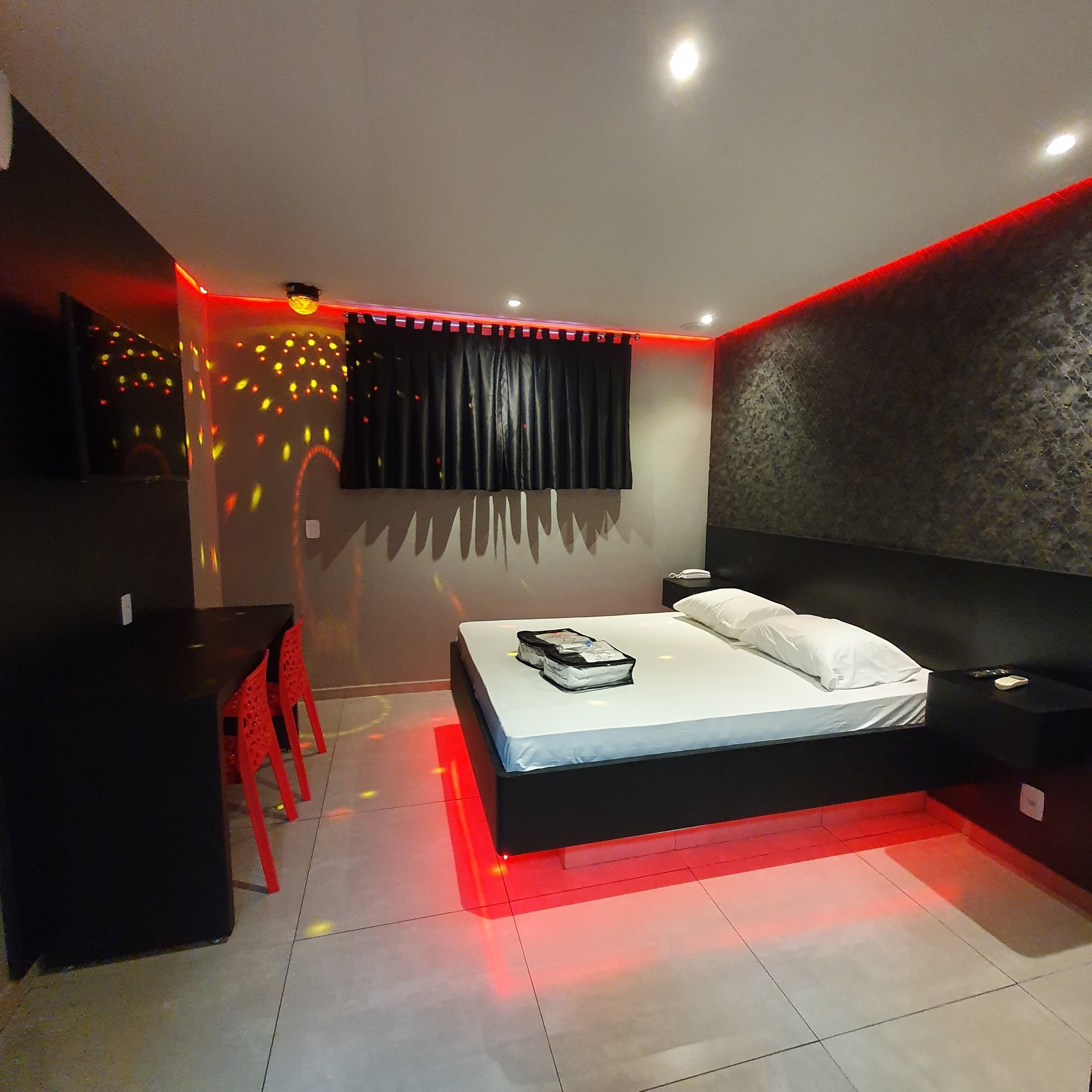 A modern bedroom with a bed, bedside tables, a desk, and a chair.